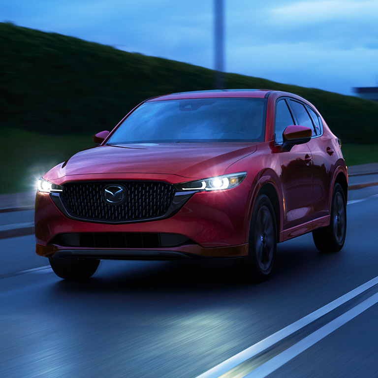 SUV roja con faros prendidos en carretera